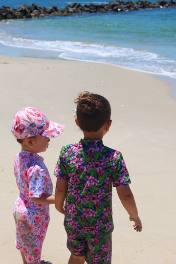 2 girls wearing midnight bloom and coral garden UPF 50+ rash sets at the beach